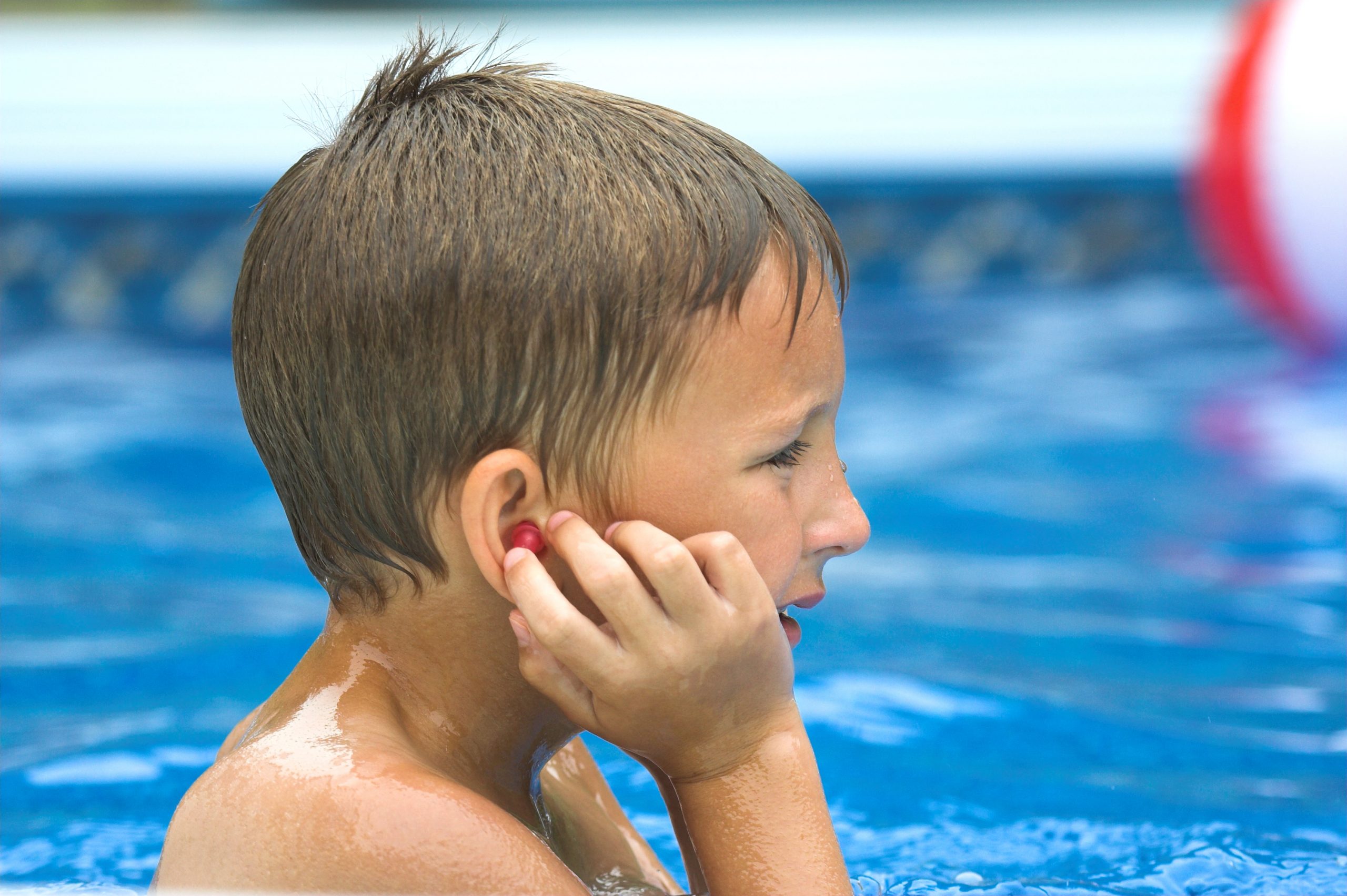 a child clutching his ear while swimming in a pool