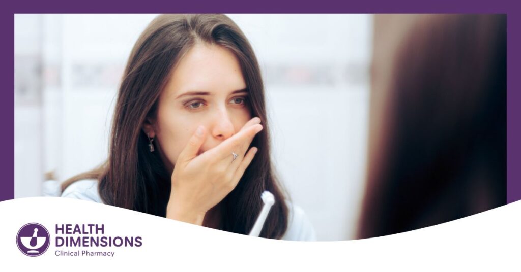 Woman holding toothbrush while looking at the mirror